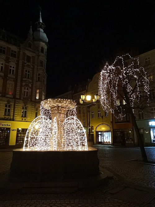 Świdnica. Rynek w świątecznej iluminacji - jedna z czterech narożnych fontann, fragment pierzei południowej, wylot ulicy Długiej, narożna kamienica pierzei wschodniej #DolnyŚląsk #zabytki #Świdnica #Schweidnitz #rynek #starówka #święta